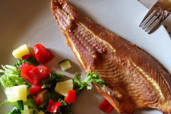 Savustettu kala lautasella, jossa on salaattia.